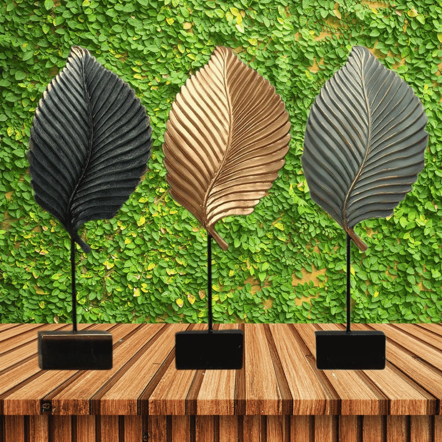 Three leaf-shaped decorative items on stands against a green leafy background