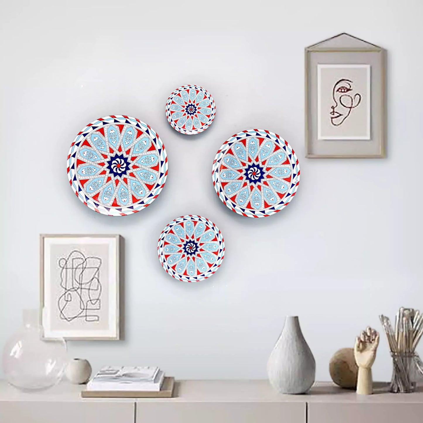 Decorative plates with geometric patterns on a wall with framed art and vases.
