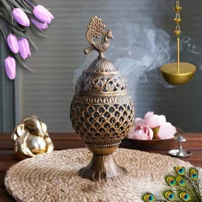 Bronze incense burner with smoke on a dark background with pink flowers and petals.