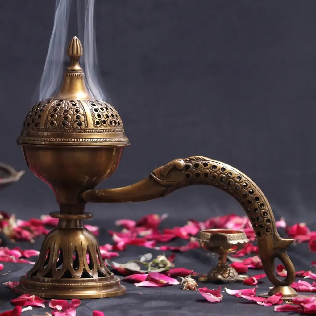 Decorative brass incense burner with smoke on a dark background with pink petals.