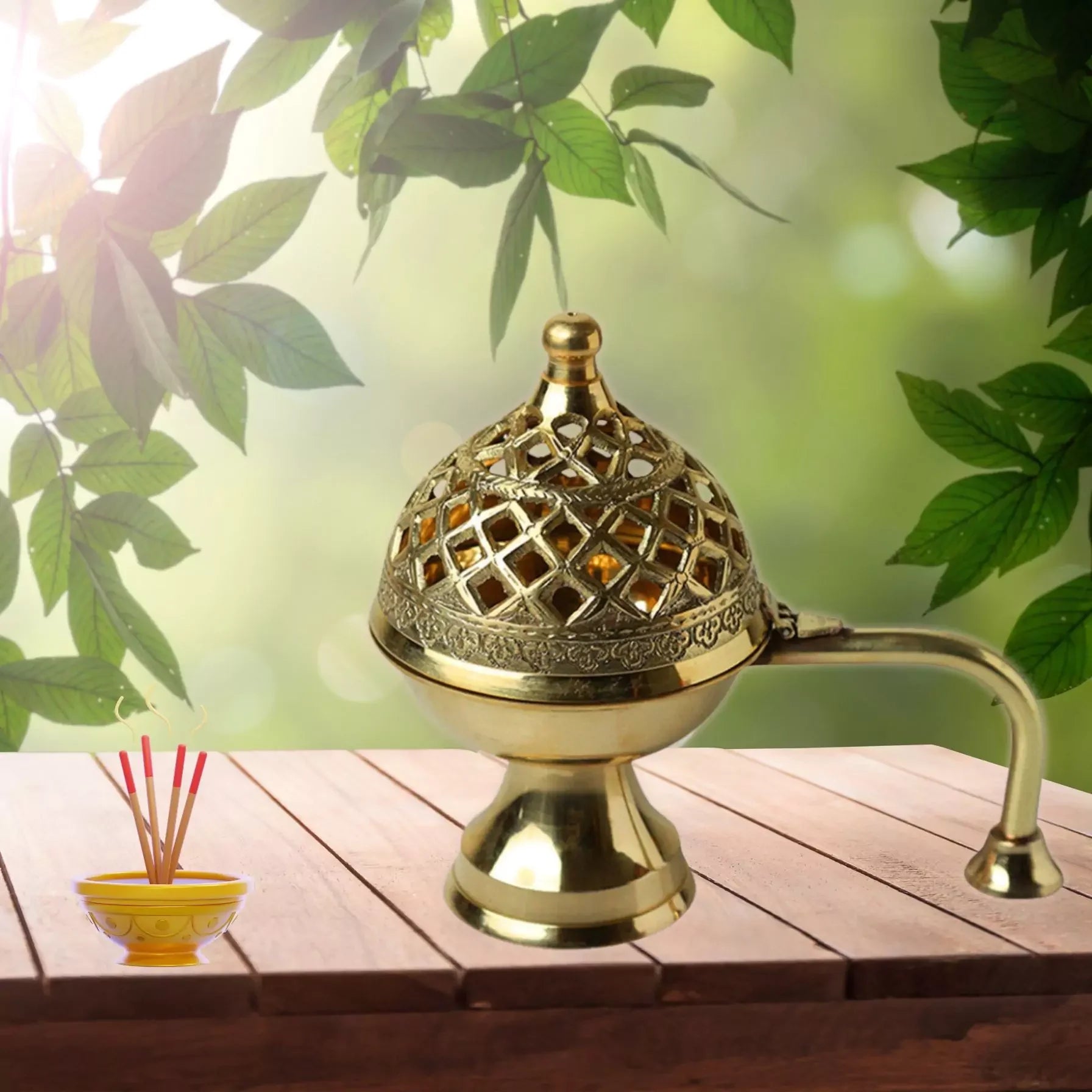 Decorative gold incense burner on a wooden surface with green leaves in the background