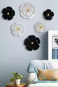 Decorative wall flowers on a light blue wall with a couch and plant in the foreground.