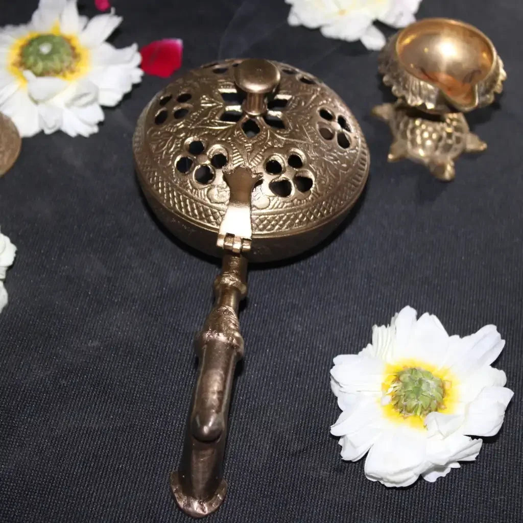Bronze incense burner with floral decorations on a dark background