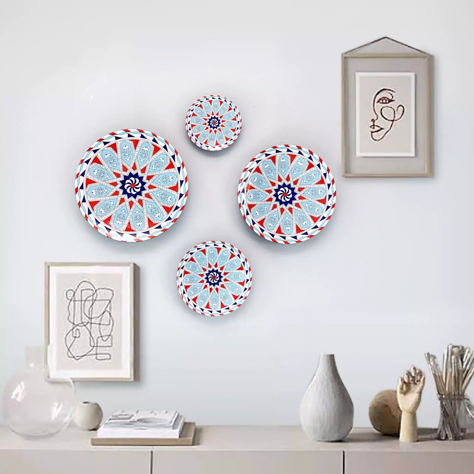 Decorative plates with geometric patterns on a wall with framed art and vases.